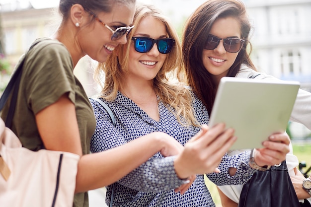 Groep stijlvolle vrouwen die genieten in de stad en een digitale tablet gebruiken