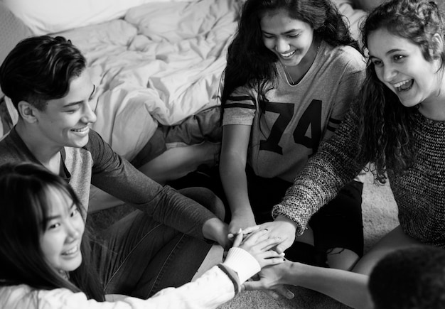 Groep tieners in een slaapkamer die hun handen samen gemeenschap en temwork concept zetten