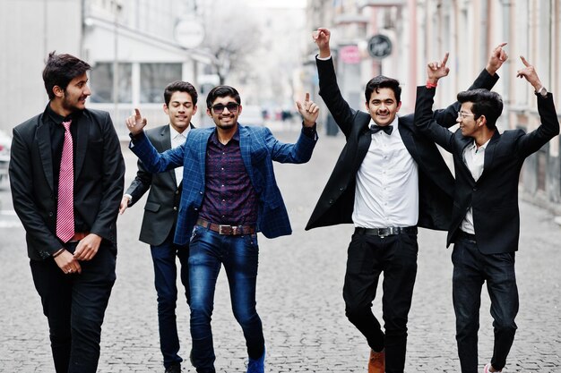 Groep van 5 Indiase studenten in pakken poseerden buiten met plezier en dansen