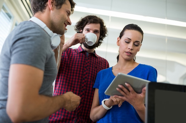 Groep van grafische ontwerpers met behulp van digitale tablet onder het genot van koffie