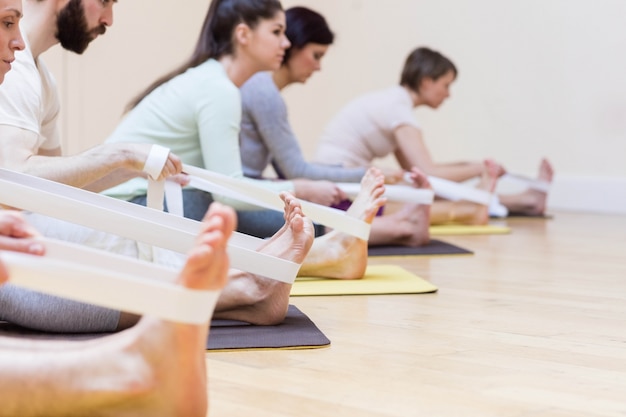 Gratis foto groep van mensen die het uitvoeren stretching oefening op oefening mat