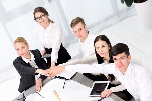 Groep van mensen uit het bedrijfsleven stapelen elkaar overhandigen aan het bureau