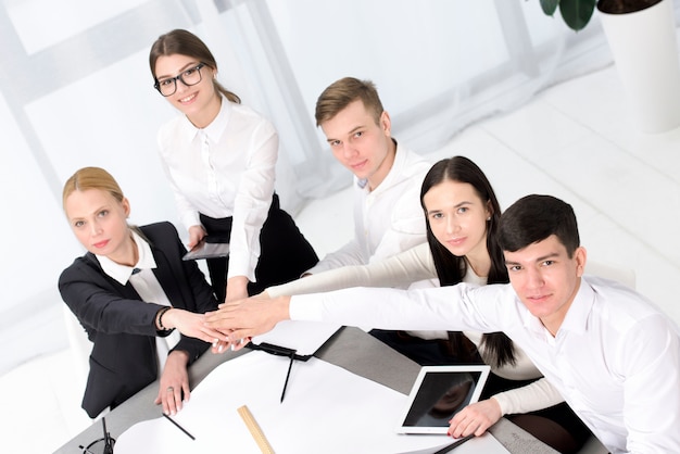 Groep van mensen uit het bedrijfsleven stapelen elkaar overhandigen aan het bureau