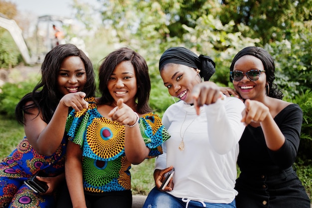 Groep van vier Afro-Amerikaanse meisjes die buiten zitten en vingers tonen