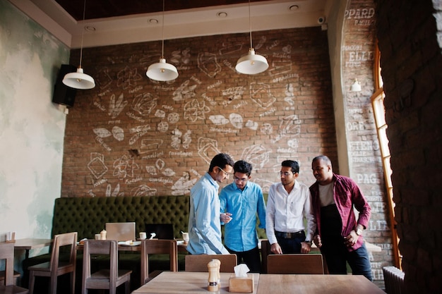 Groep van vier Zuid-Aziatische mannen poseerden op zakelijke bijeenkomst in café-indianen die een gesprek hadden