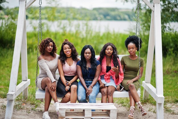 Groep van vijf Afro-Amerikaanse meisjes ontspannen op mooie schommel