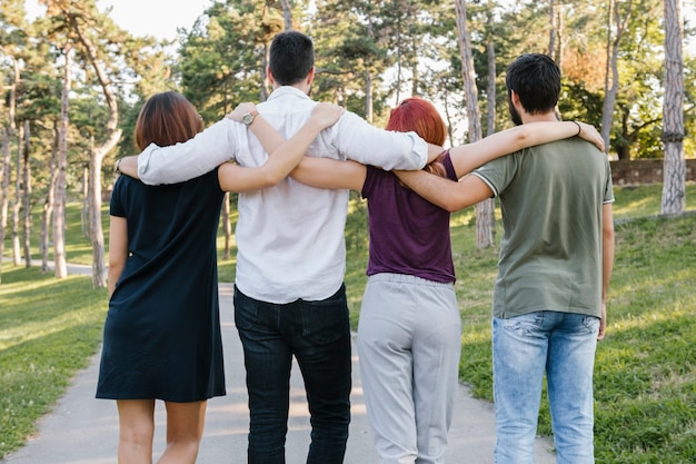 Groep volwassen vrienden knuffelen en wandelen langs de weg