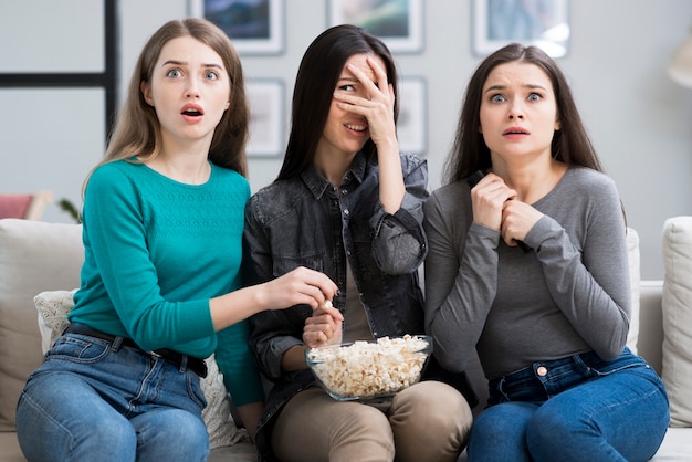 Groep volwassen vrouwen die op een griezelfilm letten