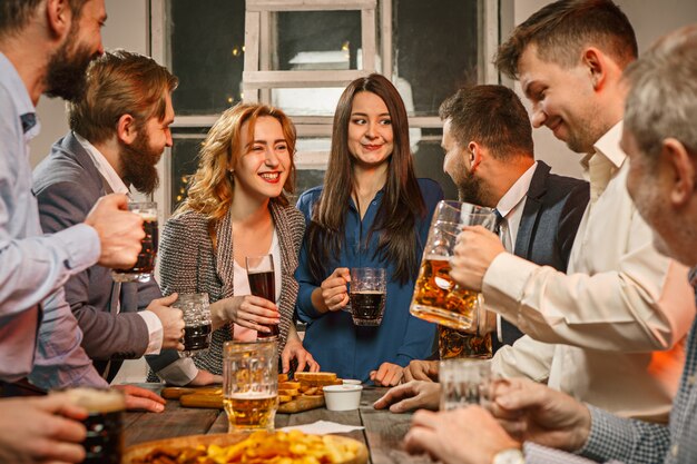 Groep vrienden die avond van dranken met bier op houten lijst genieten