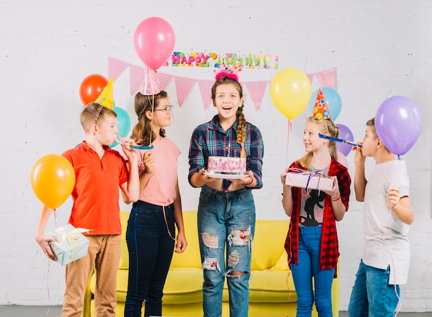 Groep vrienden die de cake van de meisjesholding verjaardag bekijken