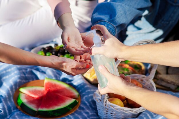 Groep vrienden die handen desinfecteren bij een picknick met lekkers