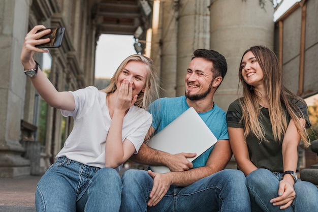 Groep vrienden die op treden zitten en een selfie nemen