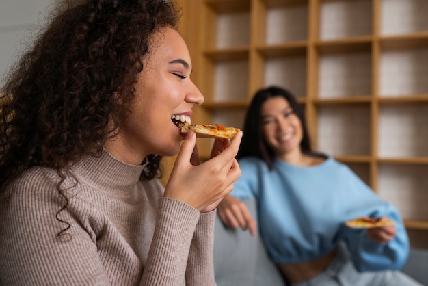 Groep vrienden die pizza thuis samen eten