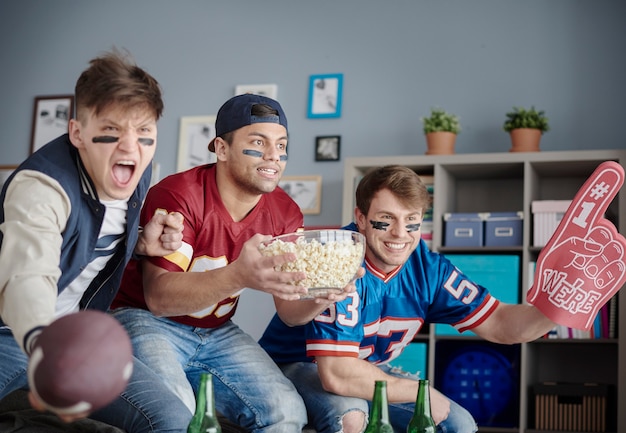 Groep vrienden die thuis voetbal kijken