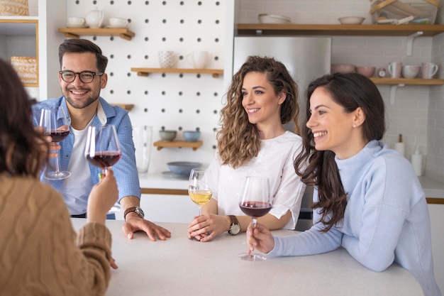 Groep vrienden die wijn drinken in de keuken