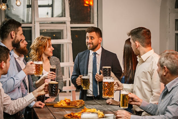 Groep vrienden genieten van drankjes in de avond met bier