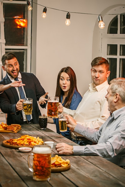 Groep vrienden genieten van drankjes in de avond met bier