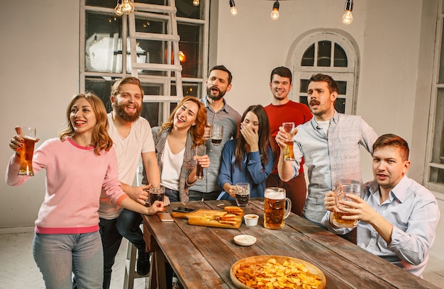 Groep vrienden genieten van 's avonds drankjes met bier op houten tafel