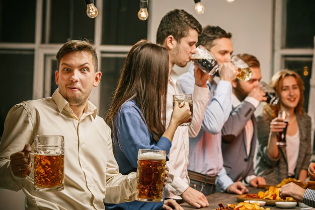 Groep vrienden genieten van 's avonds drankjes met bier op houten tafel