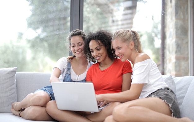 Groep vrienden glimlachen terwijl kijken naar de computer en binnen zitten