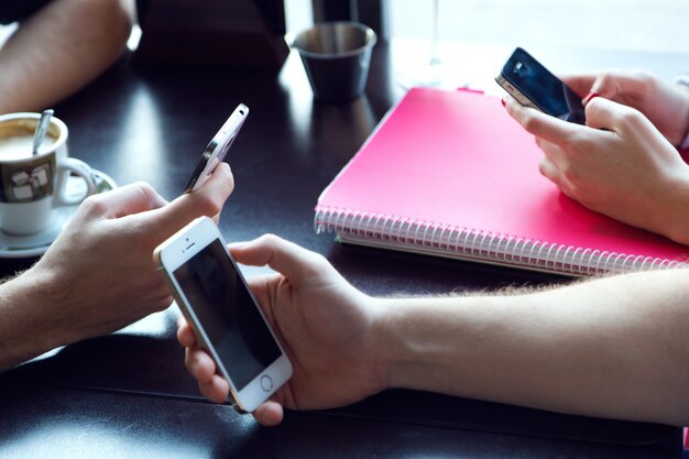 Groep vrienden met behulp van mobiele telefoon in cafe.