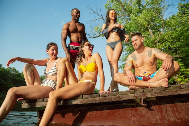 Groep vrienden opspattend water en laughting op de pier op de rivier