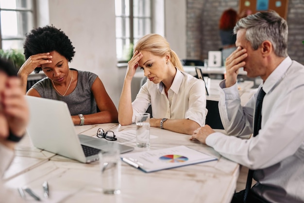 Gratis foto groep zakencollega's die hoofdpijn hebben tijdens het werken op een laptop en proberen de problemen op te lossen tijdens een vergadering