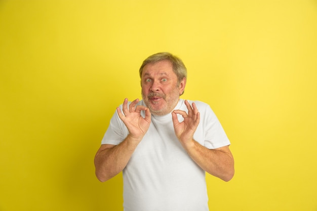 Groet, uitnodigend gebaar. Blanke man portret geïsoleerd op gele studio achtergrond. Mooi mannelijk model in wit overhemd poseren. Concept van menselijke emoties, gezichtsuitdrukking, verkoop, advertentie. Copyspace.