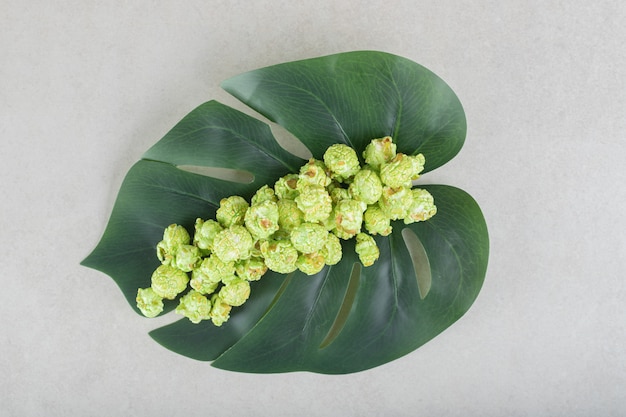 Groot decoratief blad met daarop een stapel popcornsnoepjes op marmer.