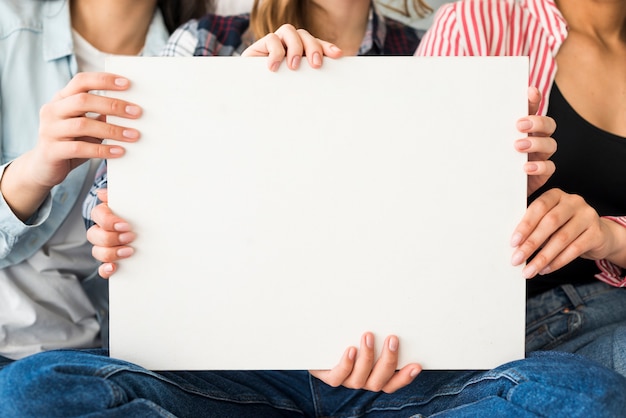 Gratis foto groot wit blad van papier dat door vrouwen houdt