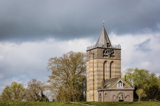 Gratis foto groothoek opname van een gebouw onder een bewolkte hemel omgeven door bomen