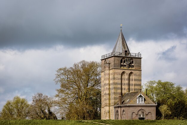 Groothoek opname van een gebouw onder een bewolkte hemel omgeven door bomen