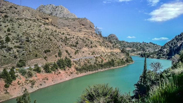 Groothoek opname van een rivier die overdag naast de bergen stroomt