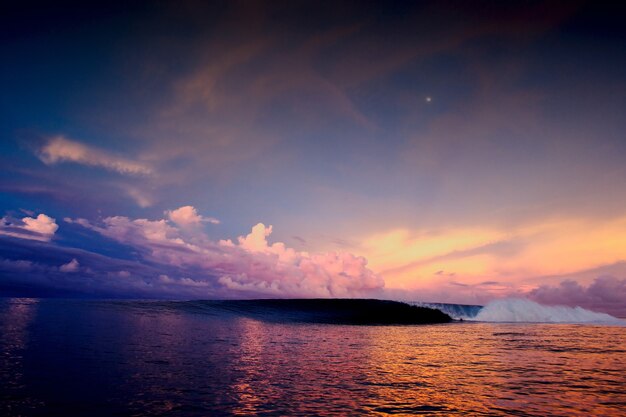 Groothoekopname van een betoverende zonsondergang in de oceaan onder een hemel vol veelkleurige wolken