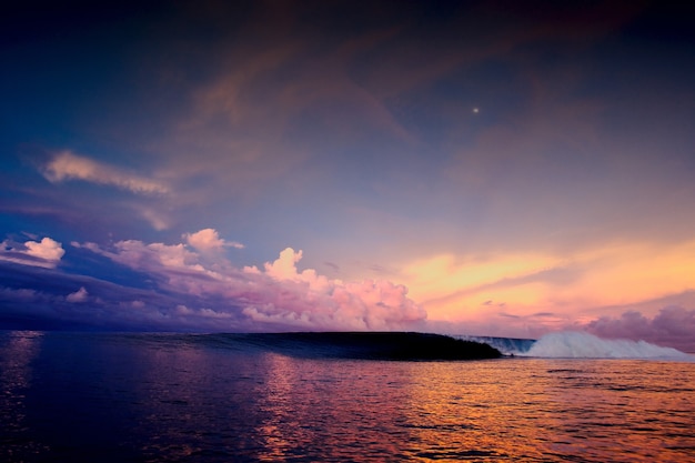 Groothoekopname van een betoverende zonsondergang in de oceaan onder een hemel vol veelkleurige wolken