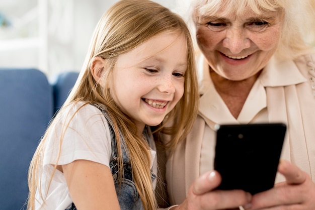 Grootmoeder en meisje mobiel kijken