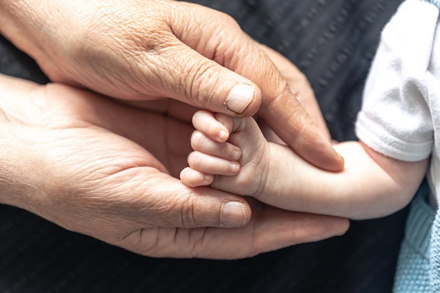 Grootmoeder houdt de hand van de baby close-up