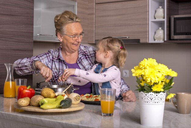 Grootmoeder speelt met haar kleindochter in de keuken