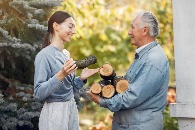 Grootvader met kleindochter op een tuin met brandhout in handen