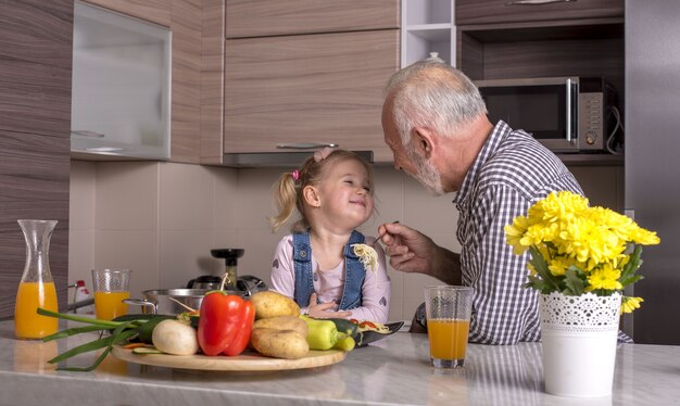 Grootvader speelt met zijn kleindochter in de keuken