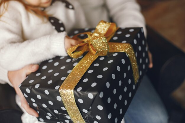 Grootvader zit met zijn kleindochter. Kerst vieren in een gezellig huis. Man in een witte gebreide trui.