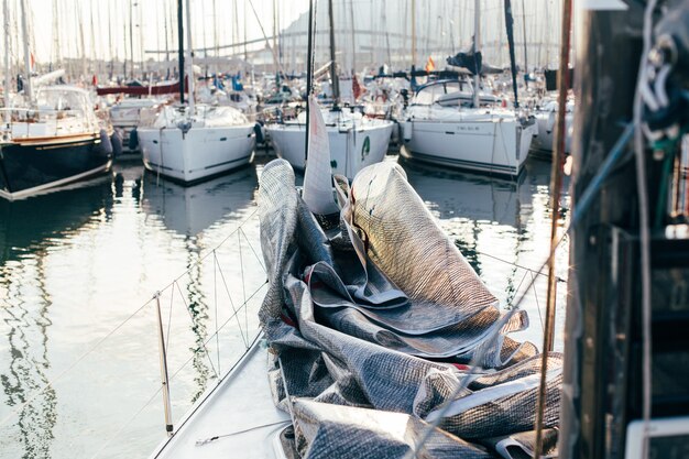 Grootzeil of spinnaker neergelegd en opgevouwen aan dek van professionele luxe zeilboot of jacht, aangemeerd in werf of jachthaven