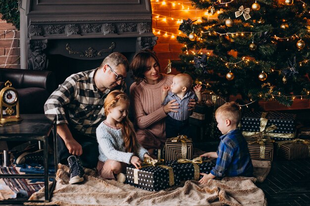 Grote familie op kerstavond met cadeautjes per kerstboom