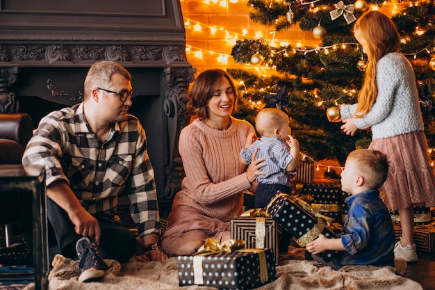 Grote familie op kerstavond met cadeautjes per kerstboom