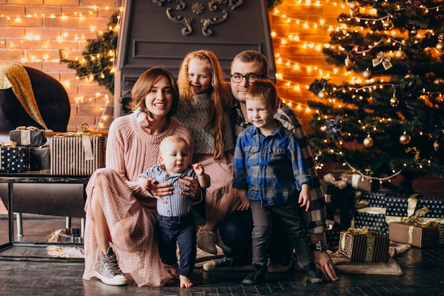 Grote familie op kerstavond met cadeautjes per kerstboom