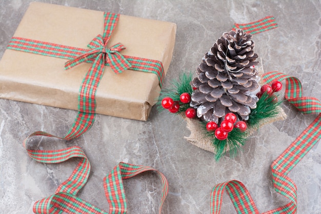 Grote feestelijke kerst pinecone met heden en strik op marmeren achtergrond.