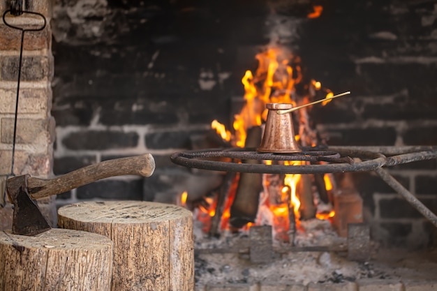 Grote open haard met een brandend vuur en turk waarin koffie wordt gezet.