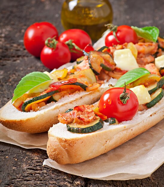 Grote sandwich met geroosterde groenten met kaas en basilicum op oude houten oppervlak