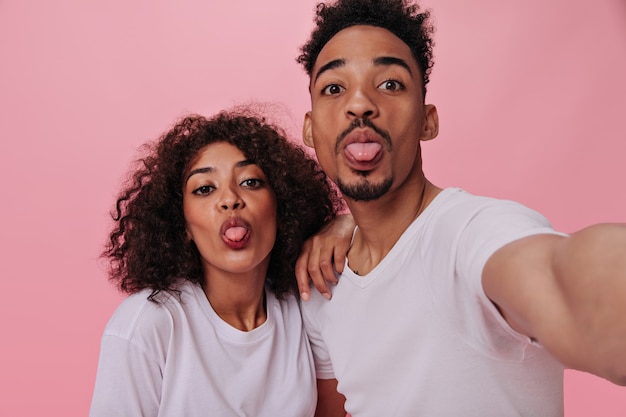 Guy en zijn vriendin gekleed in witte T-shirts met tong en selfie maken