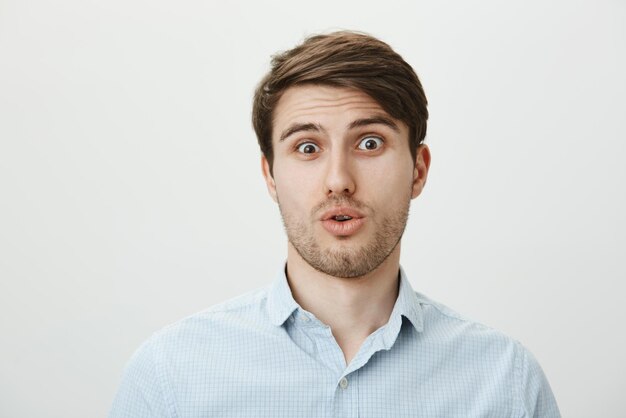 Guy is geschrokken en verbijsterd als hij iemand heel lelijk ziet. Portret van een geschokte en verwarde knappe man die zijn hoofd naar achteren kantelt